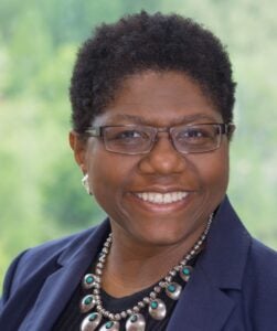 headshot image of Linda Brothers, smiling and wearing a blue jacket and glasses