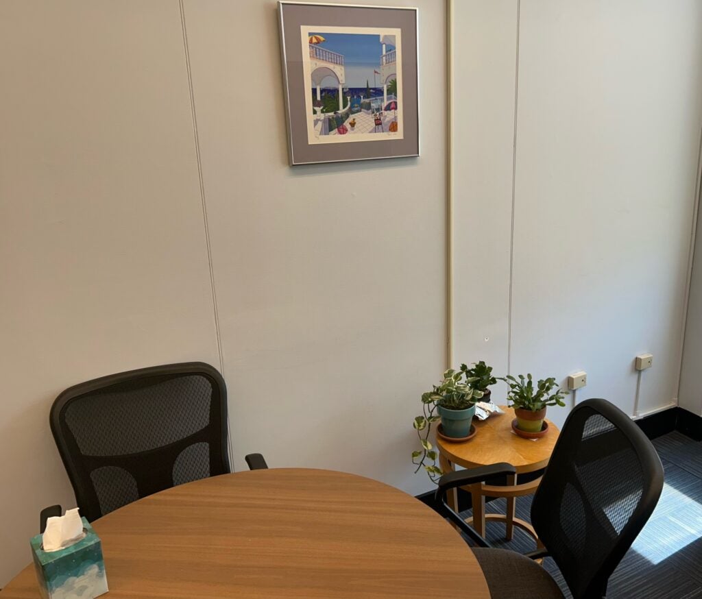 Ombuds office interior with wood table, comfortable chairs, and plants